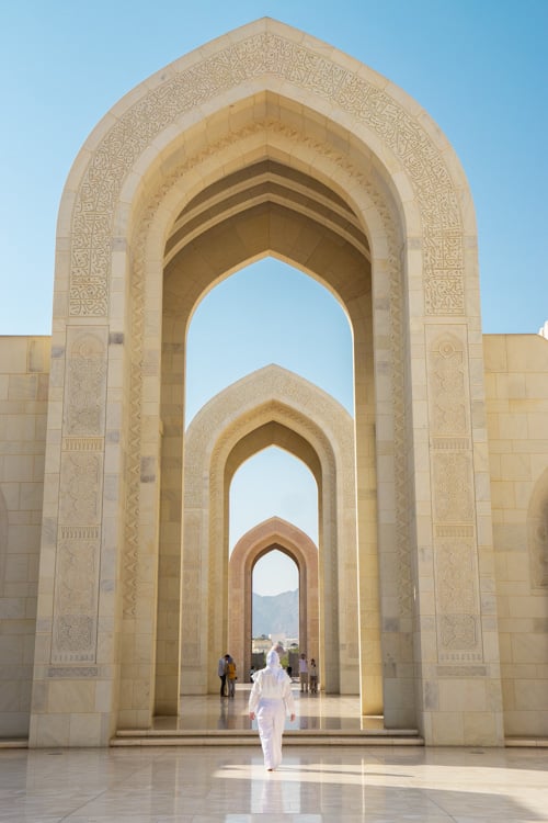 Ikzelf in het wit onder een poort van de Sultan Qaboes moskee in Muscat