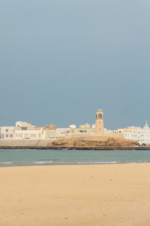 Uitzicht over strand en zee op de vuurtoren van Sur in Oman