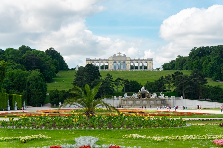 Tuin van Schloss Schönbrunn met bloemen, een palboom en fontein en Gloriette op de achtergrond