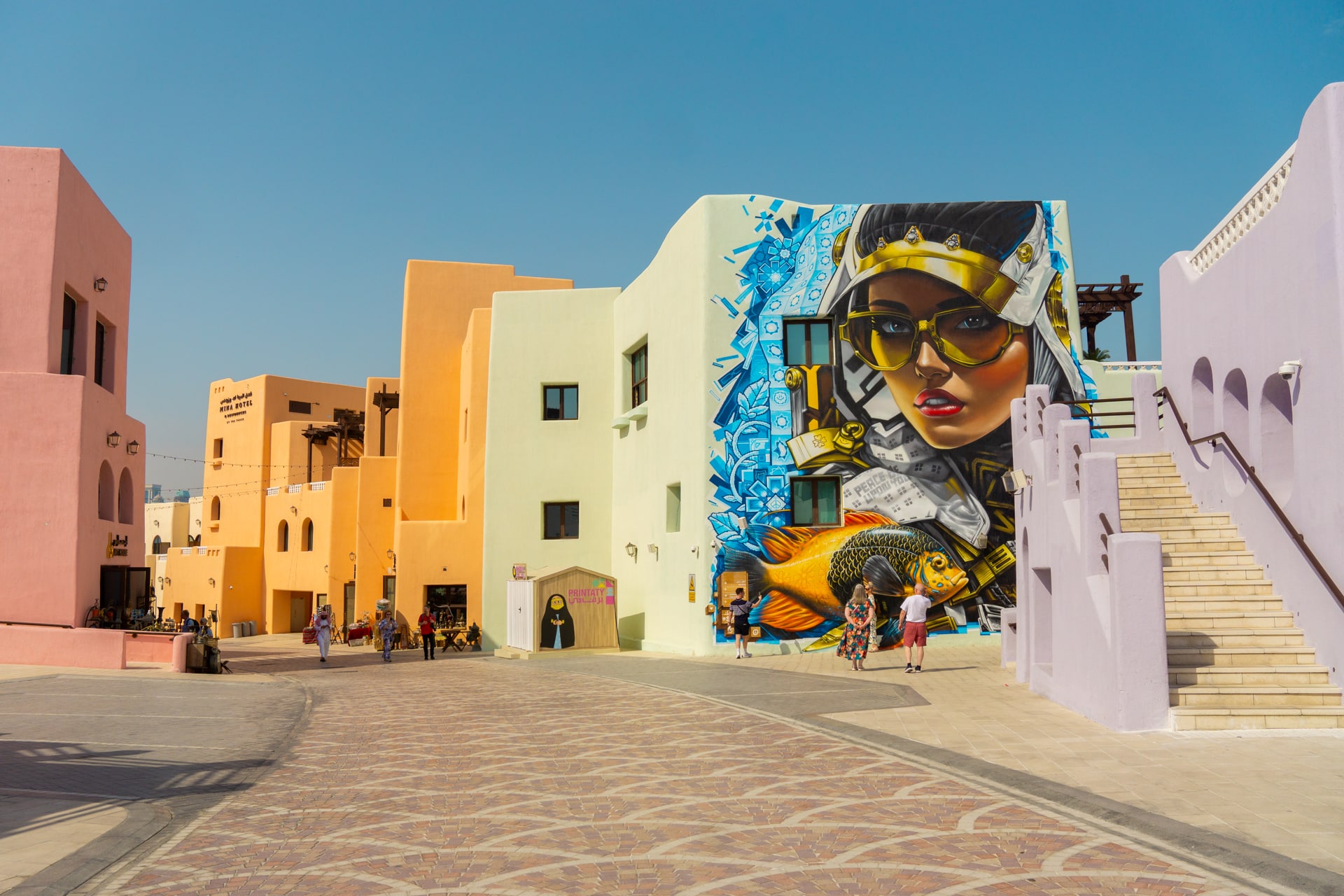 Straat met pastelkleurige gebouwen en street art. Blauwe lucht. Mina District Doha.