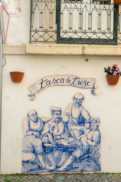 Blauwe azulejos-muurschildering met een tafereel van mensen in een Portugese taverne, met de tekst "Tasca do Treze