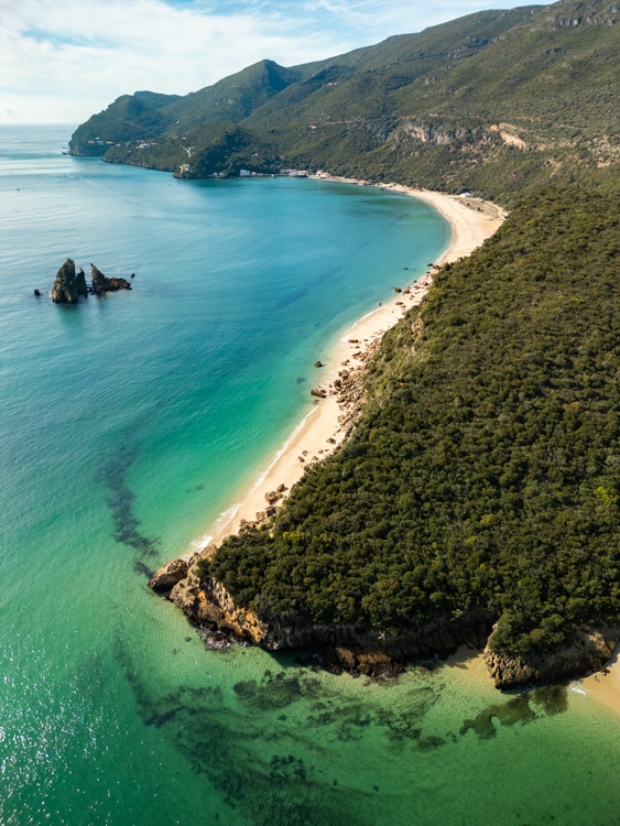 Luchtfoto van de kustlijn van Serra da Arrábida in Portugal, met een lang zandstrand, turquoise water en weelderige groene heuvels