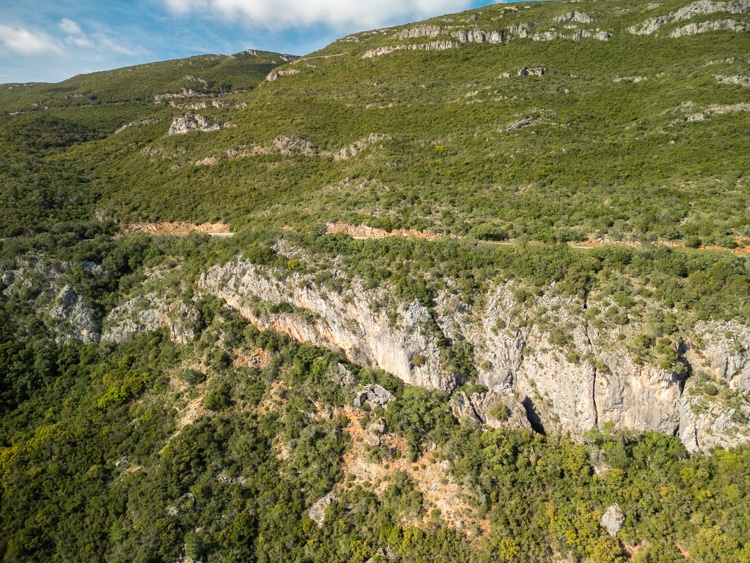 Steile rotsformaties en dichte vegetatie in het natuurpark Serra da Arrábida, Portugal, met een helderblauwe lucht op de achtergrond