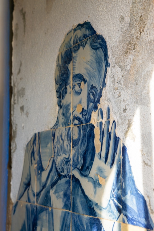 Detail van een traditionele Portugese tegel (azulejo) in het Santuário de Nossa Senhora do Cabo Espichel, met een afbeelding van een bebaarde figuur in blauwe tinten.