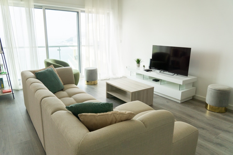 Stijlvol ingerichte woonkamer van Janelas de Zimbra in Sesimbra, Portugal, met een comfortabele bank, moderne meubels en een groot raam met uitzicht op de zee.